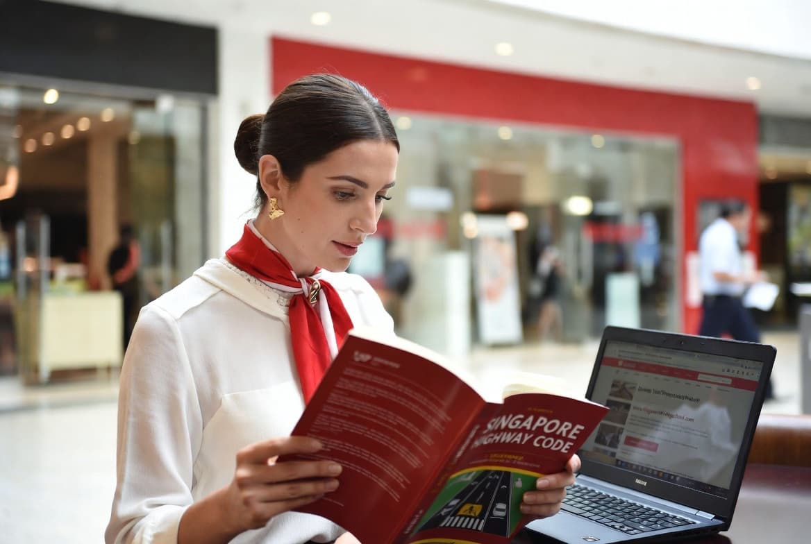Expatriate studying Singapore Highway Code at a café