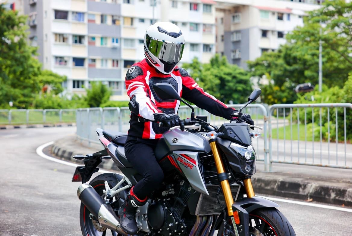 Singaporean motorcyclist in full safety gear on a modern motorcycle